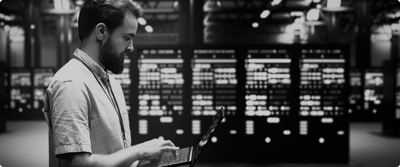 Data center technician using laptop for server monitoring and enterprise infrastructure management with AI-powered analytics